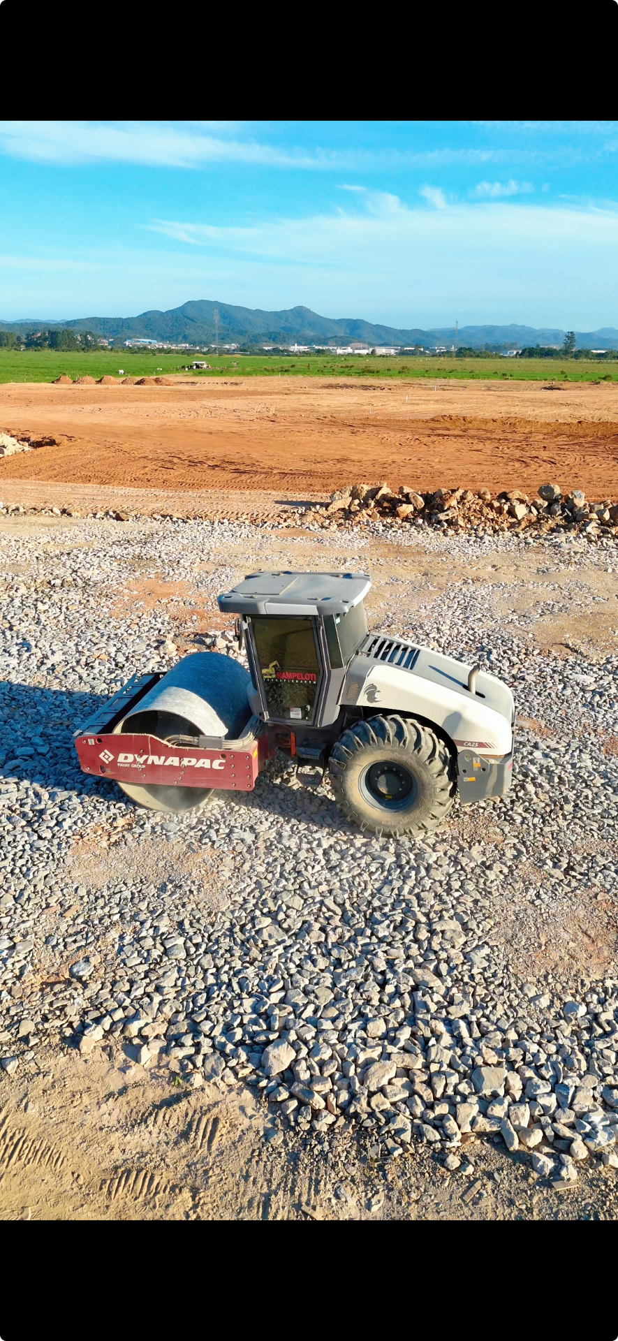 Rolo compactador operando na compactação de brita em obra da Rampeloti